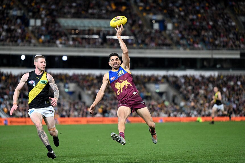 Charlie Cameron, joueur des Brisbane Lions AFL, tend la main pour lancer le ballon derrière lui à l'avantage de son équipe.