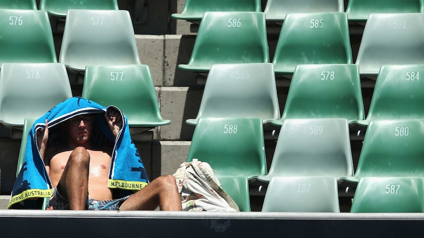 Fan shelters himself from the sun at Melbourne Park