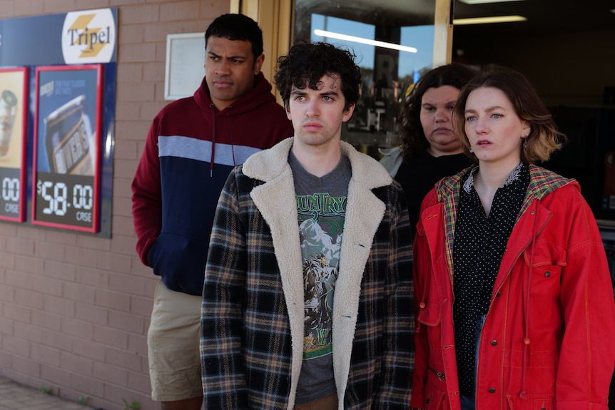 Two men and two women stand outside a bottle shop.