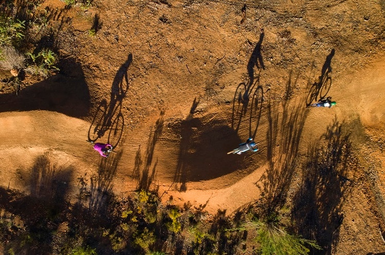 An aerial shot of three mountain bike riders riding along a dirt trail