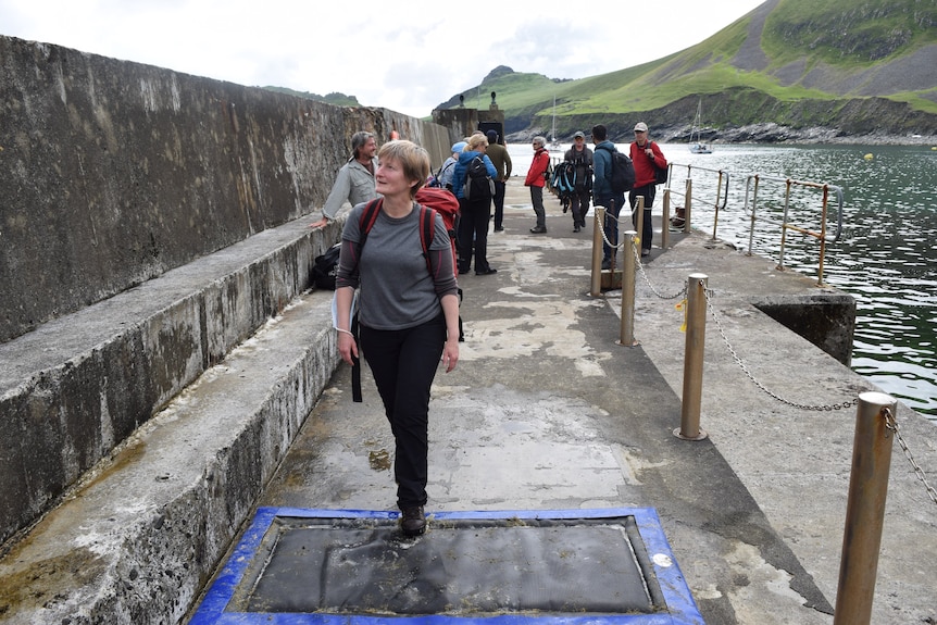 Woman casually walks across padded mad on footpath