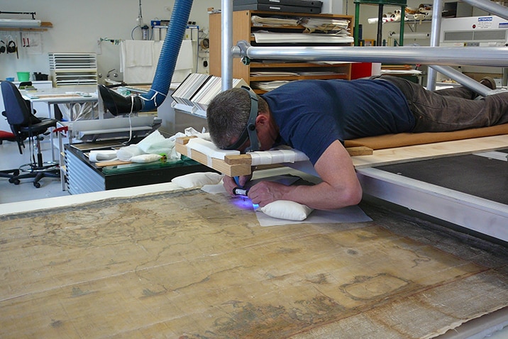 Conservator Peter Mitchelson from the Grimwade Centre removes varnish from the surface of the Blaeu map
