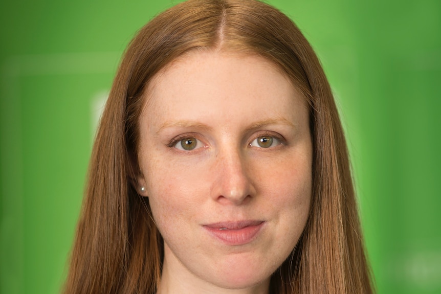 A woman with long auburn hair in front of a green background