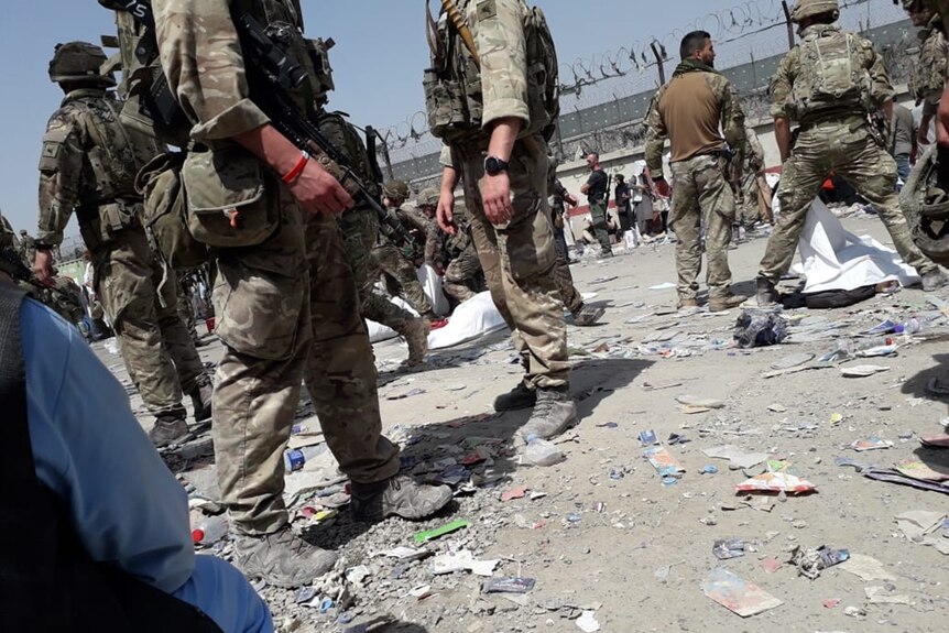 Zdjęcie przedstawiające zagranicznych żołnierzy zakrywających ciała zmarłych na lotnisku w Kabulu