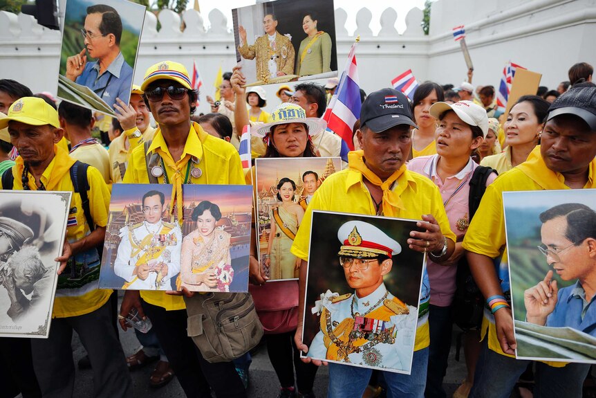Anti-government protesters wearing yellow shirts hold pictures of Thailand's King Bhumibol Adulyadej and Queen Sirikit.