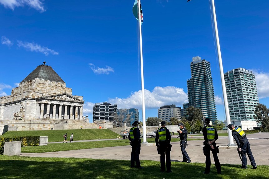 Police officers stand near flagpoles, with the Shrine in the background