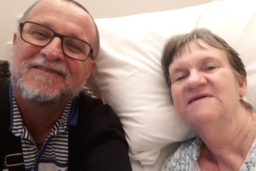 A man smiling alongside a woman in a hospital bed