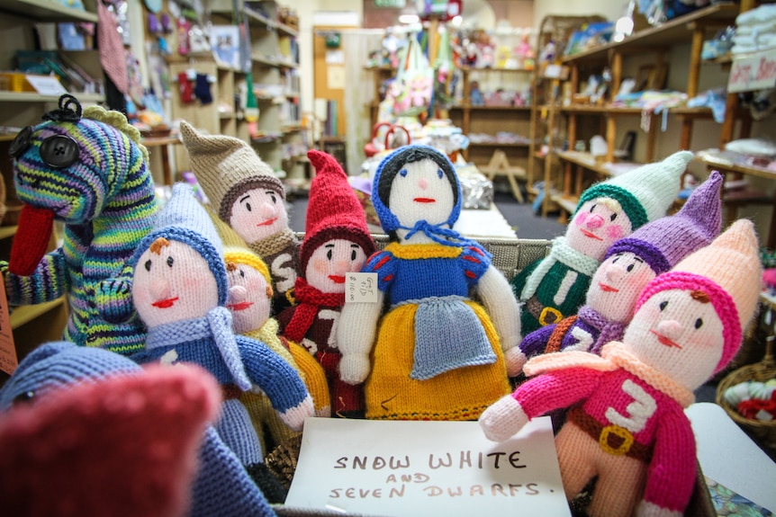 Knitted dolls representing Snow White and the Seven Dwarfs sit on a table. 