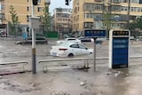A screengrab from a video showing a car floating down a flooded street street in Beijing.  