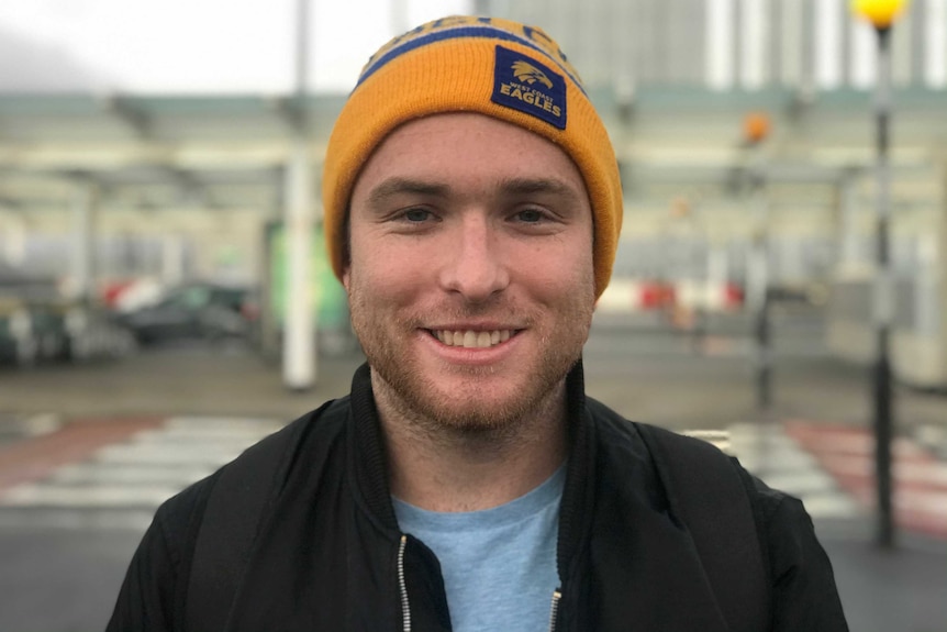 A man smiles, he is wearing a West Coast Eagles beanie.