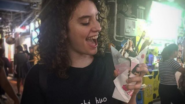 A young woman smiles as she looks at an ice cream sundae.