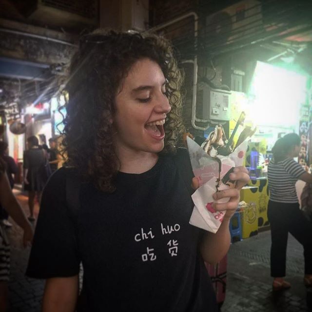 A young woman smiles as she looks at an ice cream sundae.