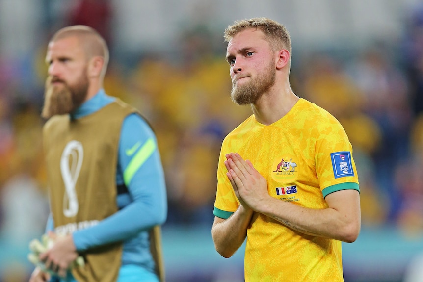 Nathaniel Atkinson puts his hands together and looks sad as he walks on the pitch after the Socceroos' World Cup loss to France.