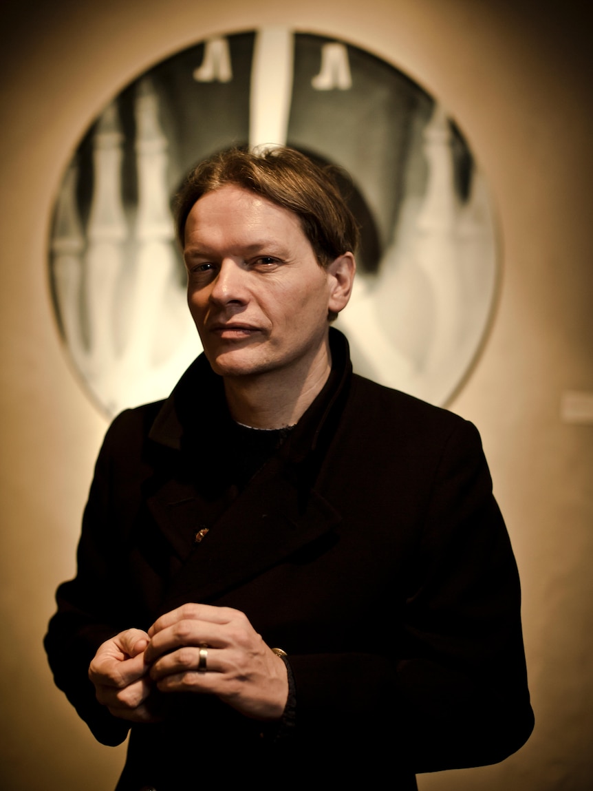 Portrait of a white man with dark hair wearing a heavy coat.