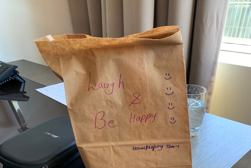 A brown paper bag with a handwritten message on it that reads 'laugh and be happy'.