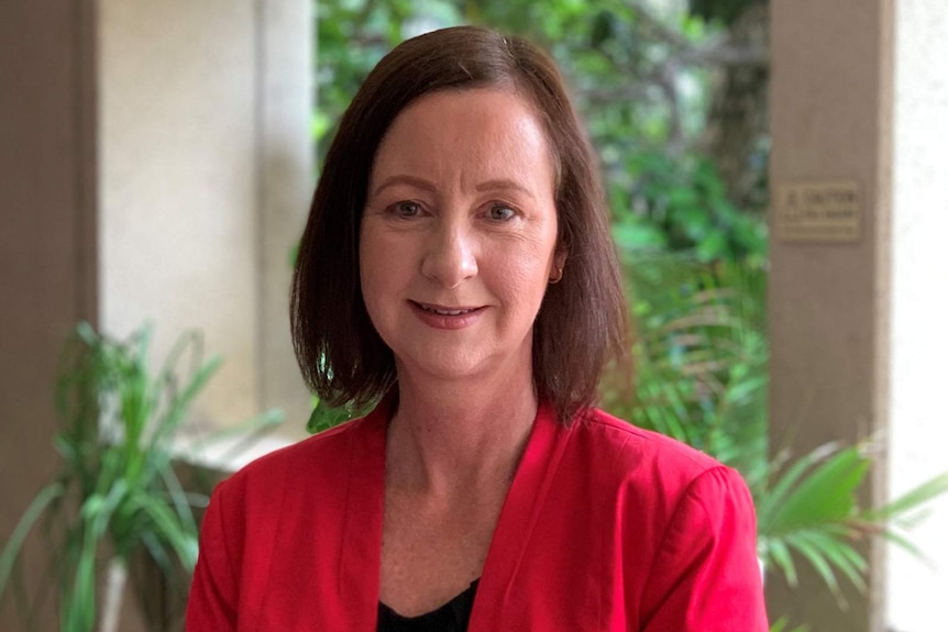 A headshot of a woman in a red business jacket