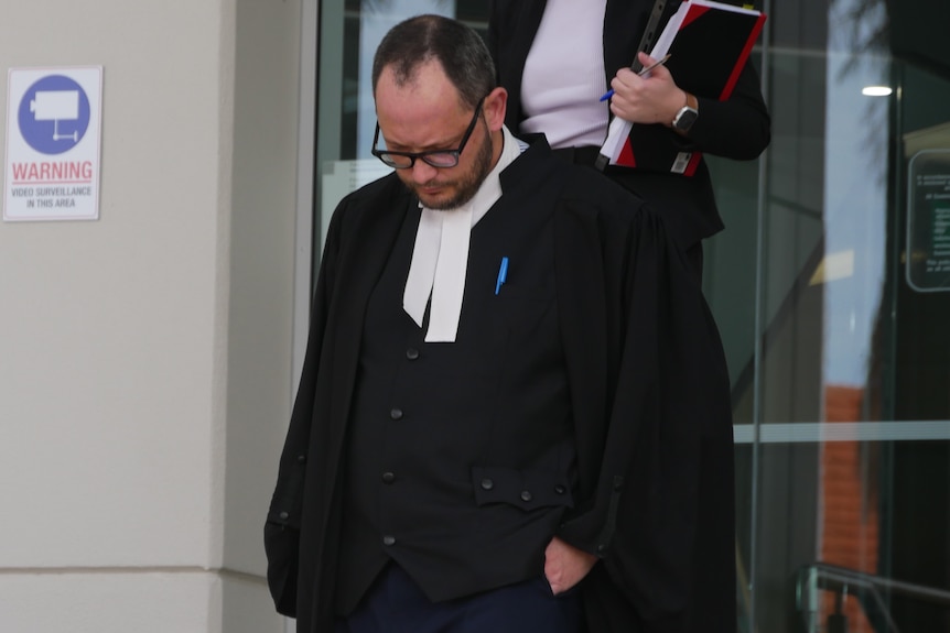 A man in black robes and glasses walking down steps 