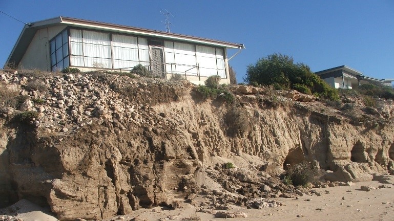 A white beach shack just few meters away from a cliff caused by storm erosion at Point Turton in South Australia.