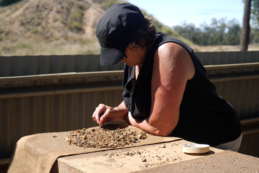 Woman searching a table of rocks with tweezers.
