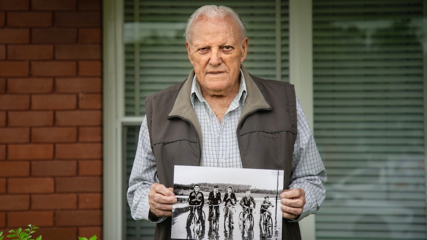 Ted Books holds up a black and white photograph outside a home.