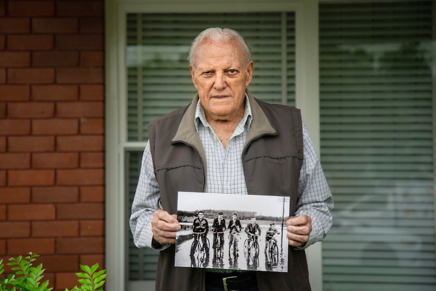 Ted Books holds up a black and white photograph outside a home.