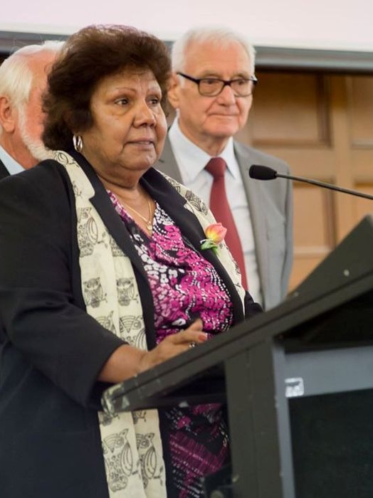 Aboriginal elder Aunty Lillian Burke stands at a lectern giving a speech for her award from Volunteering Queensland.