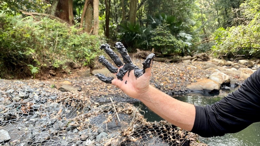 A hand covered in a black oily substance