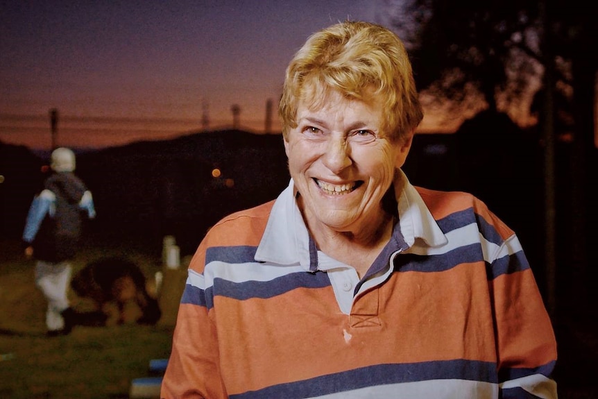 A woman smiles at an oval at dusk.