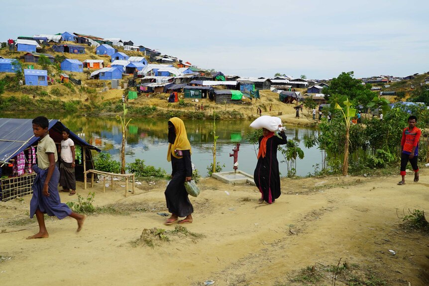 Refugees walk passed a "contaminated" Balukhali reservoir.