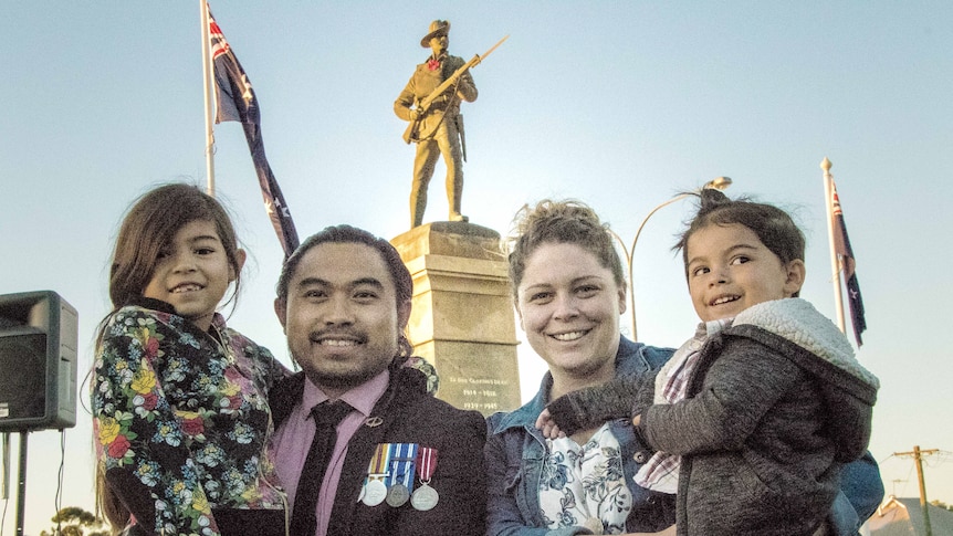 Army veteran with family in front of war memorial
