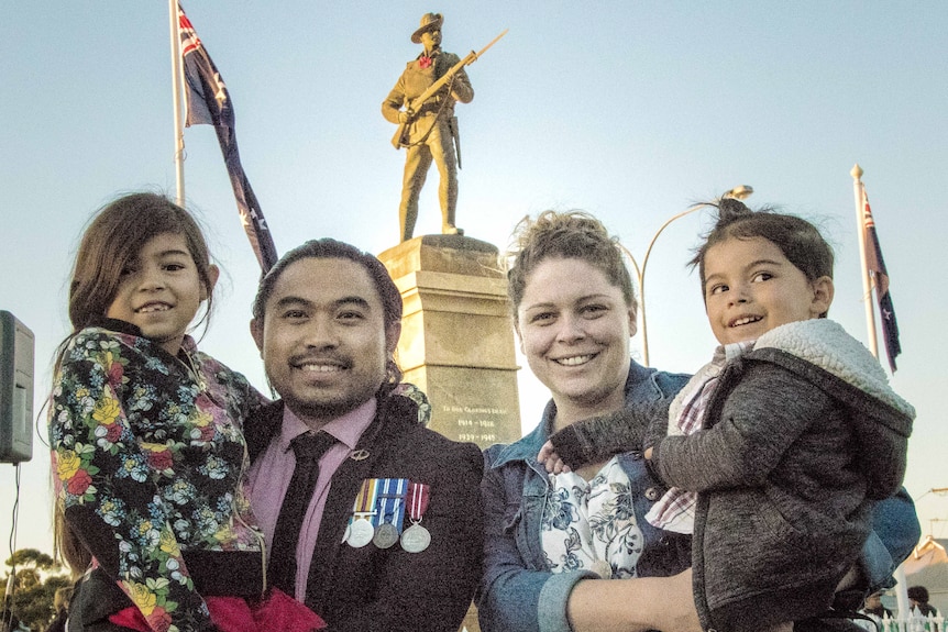 Army veteran with family in front of war memorial