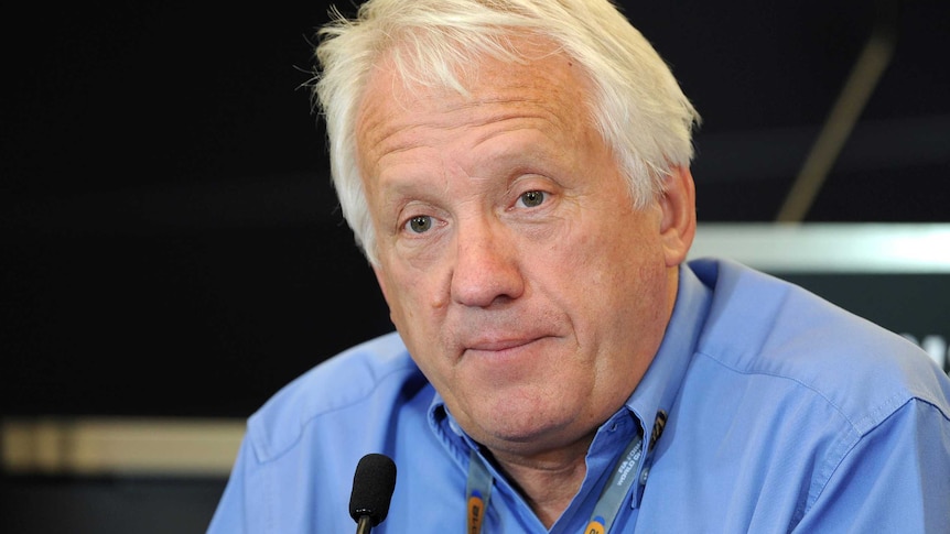 Charlie Whiting over a microphone at a press conference.