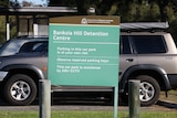 A Banksia Hill Detention Centre sign, with cars in the background.