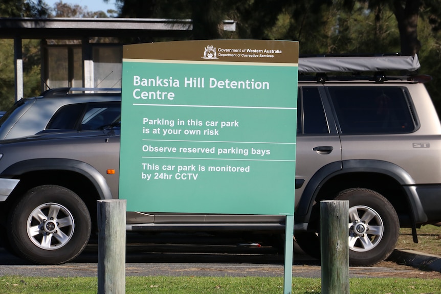 A Banksia Hill Detention Centre sign, with cars in the background.