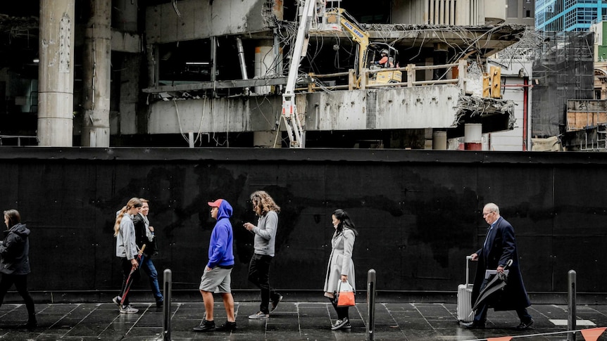 city people walking past a construction zone