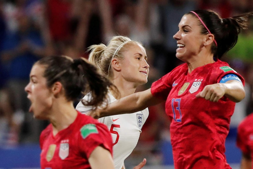 Steph Houghton looking dismayed as Alex Morgan and Kelley O'Hara celebrate in the foreground.