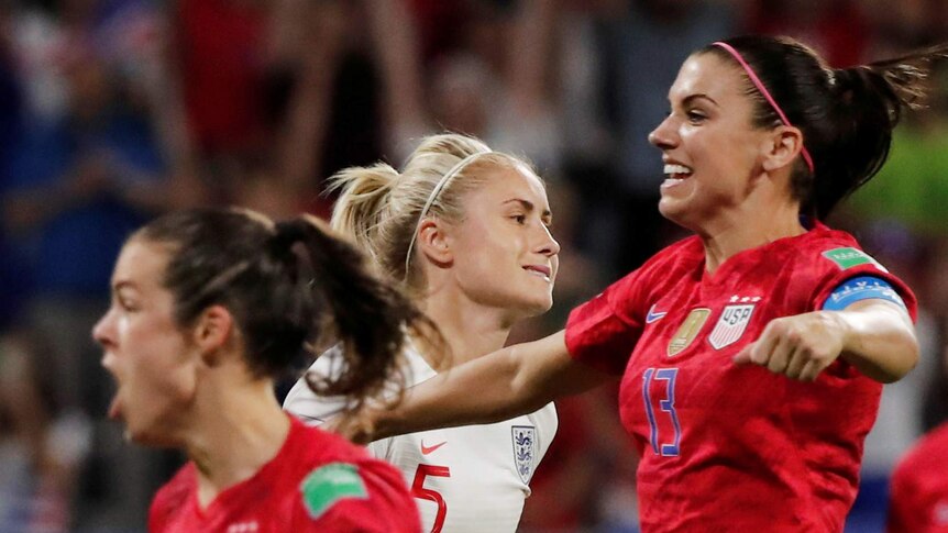 Steph Houghton looking dismayed as Alex Morgan and Kelley O'Hara celebrate in the foreground.