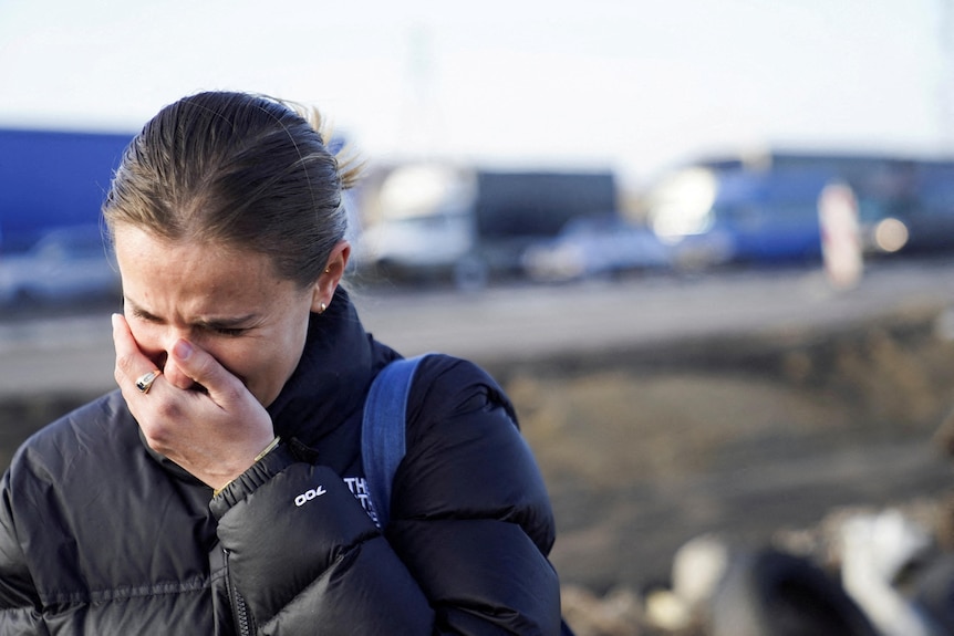 A woman cried with her face covering her mouth and her head down. 