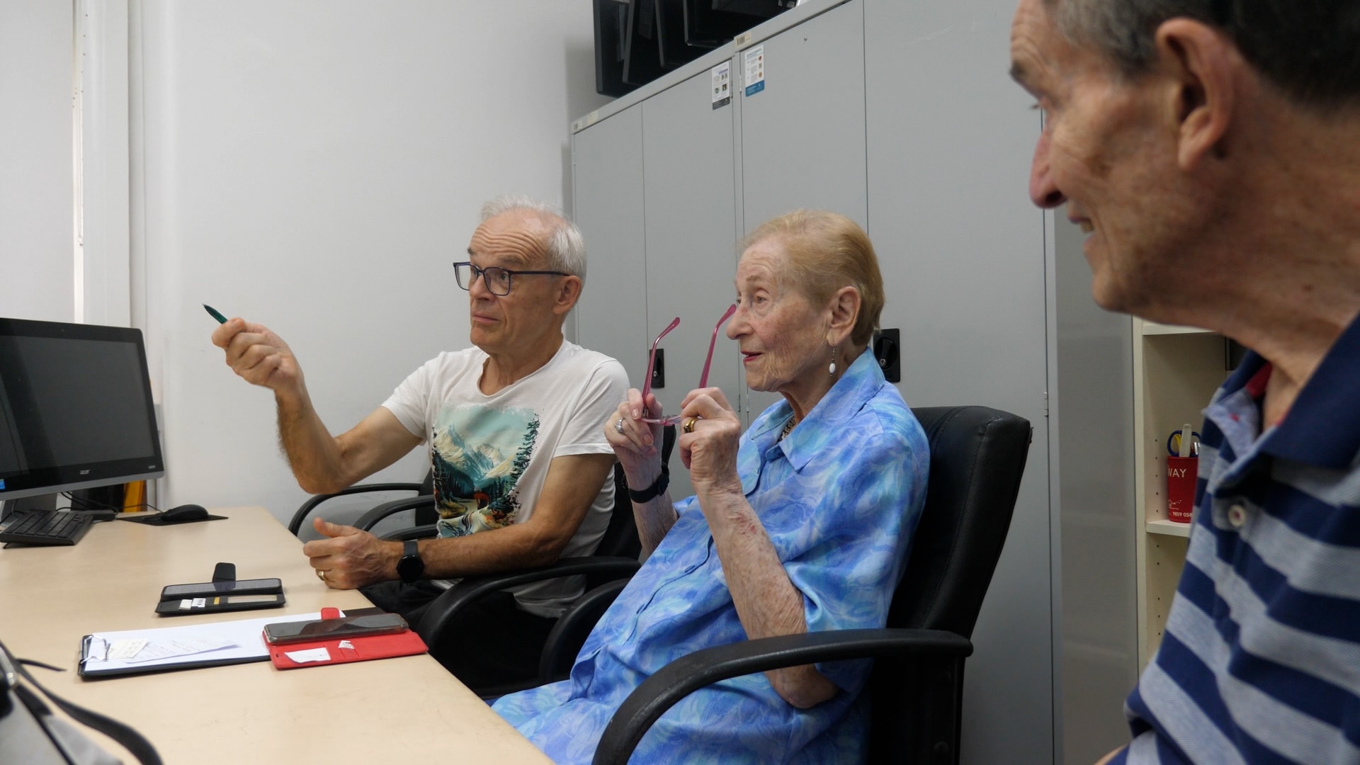 Un hombre hace un gesto hacia adelante mientras está sentado junto a dos personas mayores.