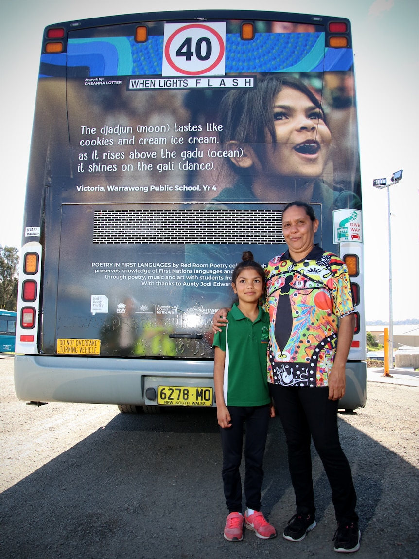 Victoria and Dorothy Thomas stand in front of the bus with Victoria's poem on the back.