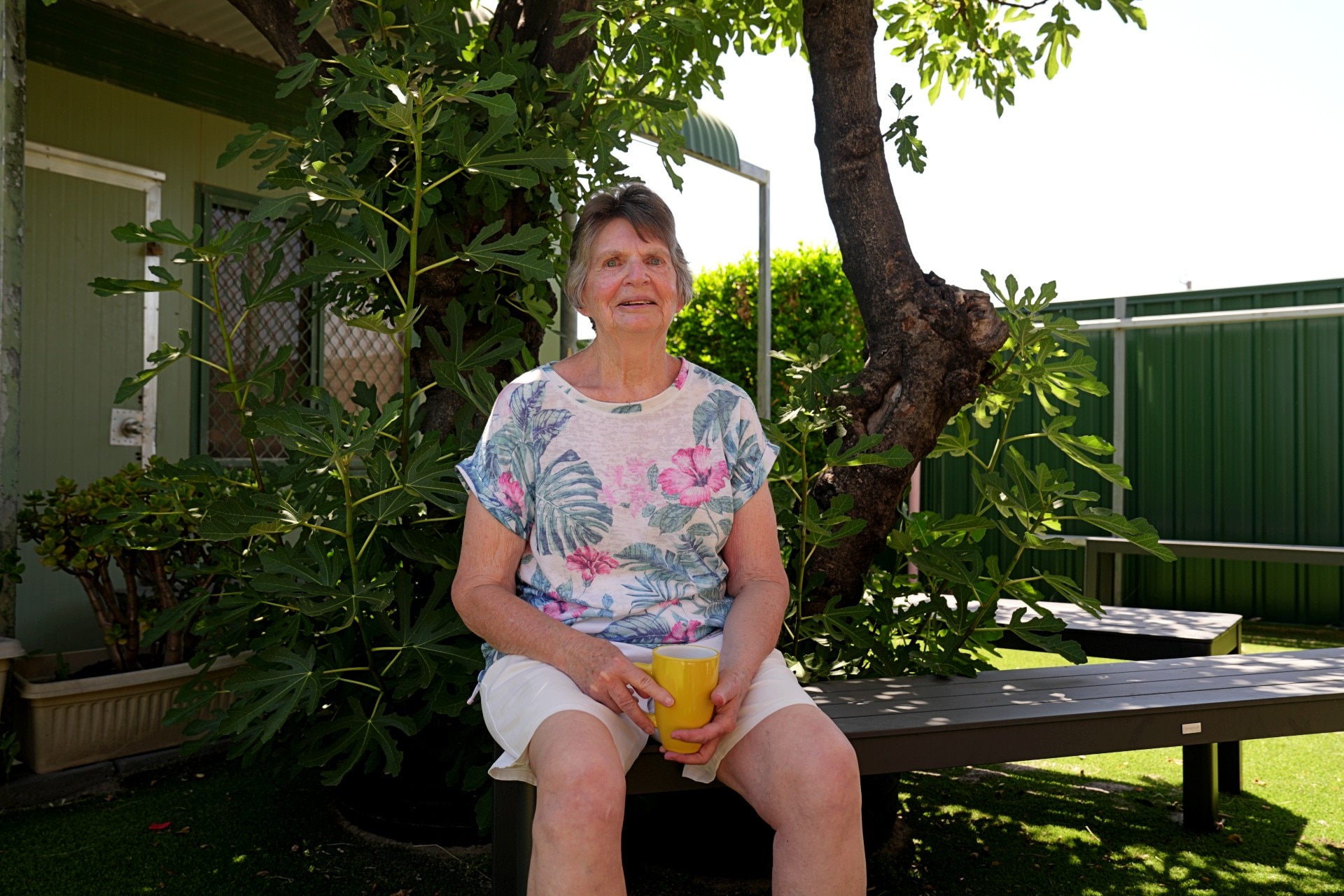 An older woman sits down smiling.
