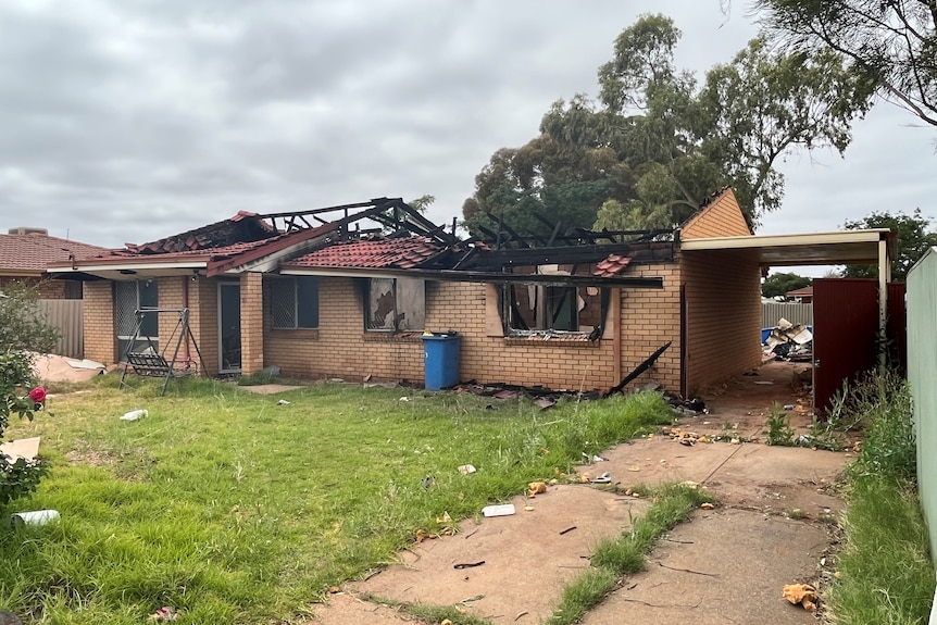 a light brick house with a burnt out roof and windows 