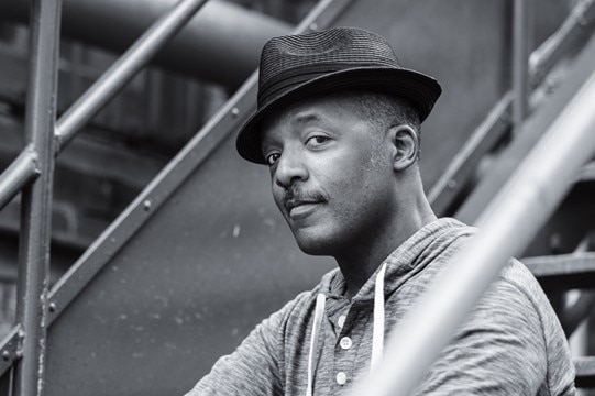 Actor Madison McKoy sits on a metal staircase in a black and white picture.