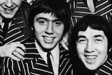 The members of the Easybeats smile in a black and white promo photo, wearing matching striped jackets.