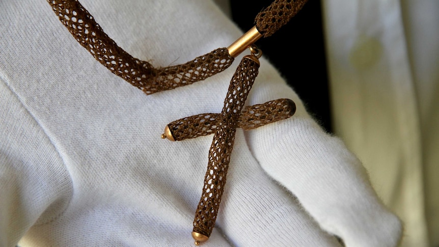 Human hair woven into a braided necklace with a crucifix