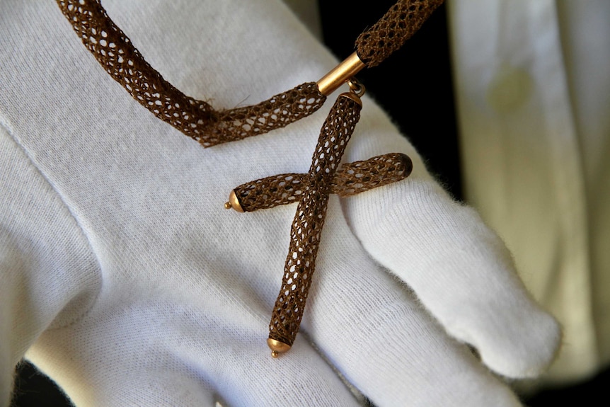 Human hair woven into a braided necklace with a crucifix