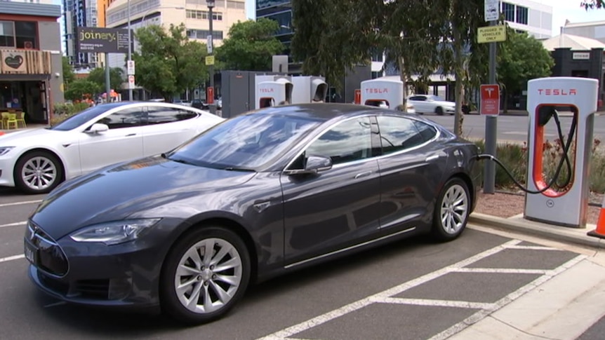 A dark grey car parked at an electric charging station