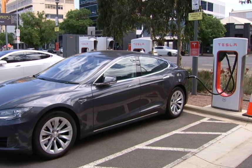 A dark grey car parked at an electric charging station