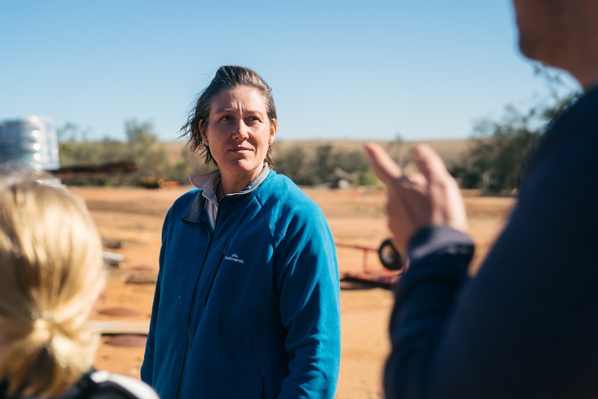 Jessica wears a blue jumper while assessing damage from a cyclone.