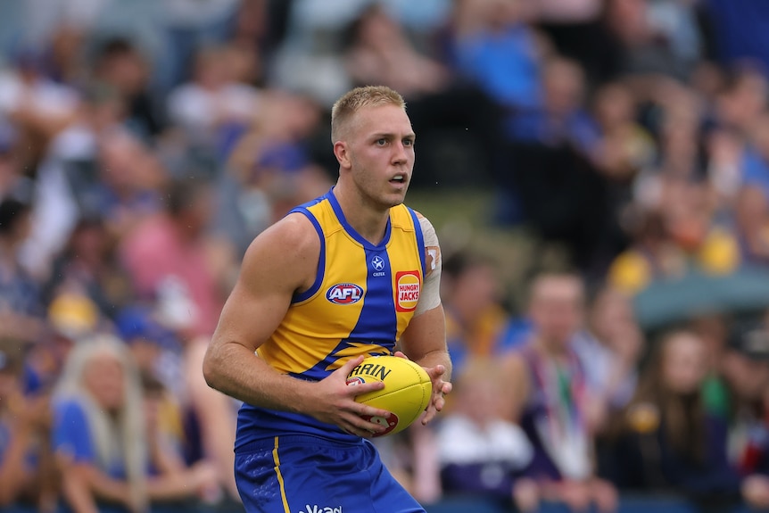 West Coast Eagles player Oscar Allen holds the ball during a game. 